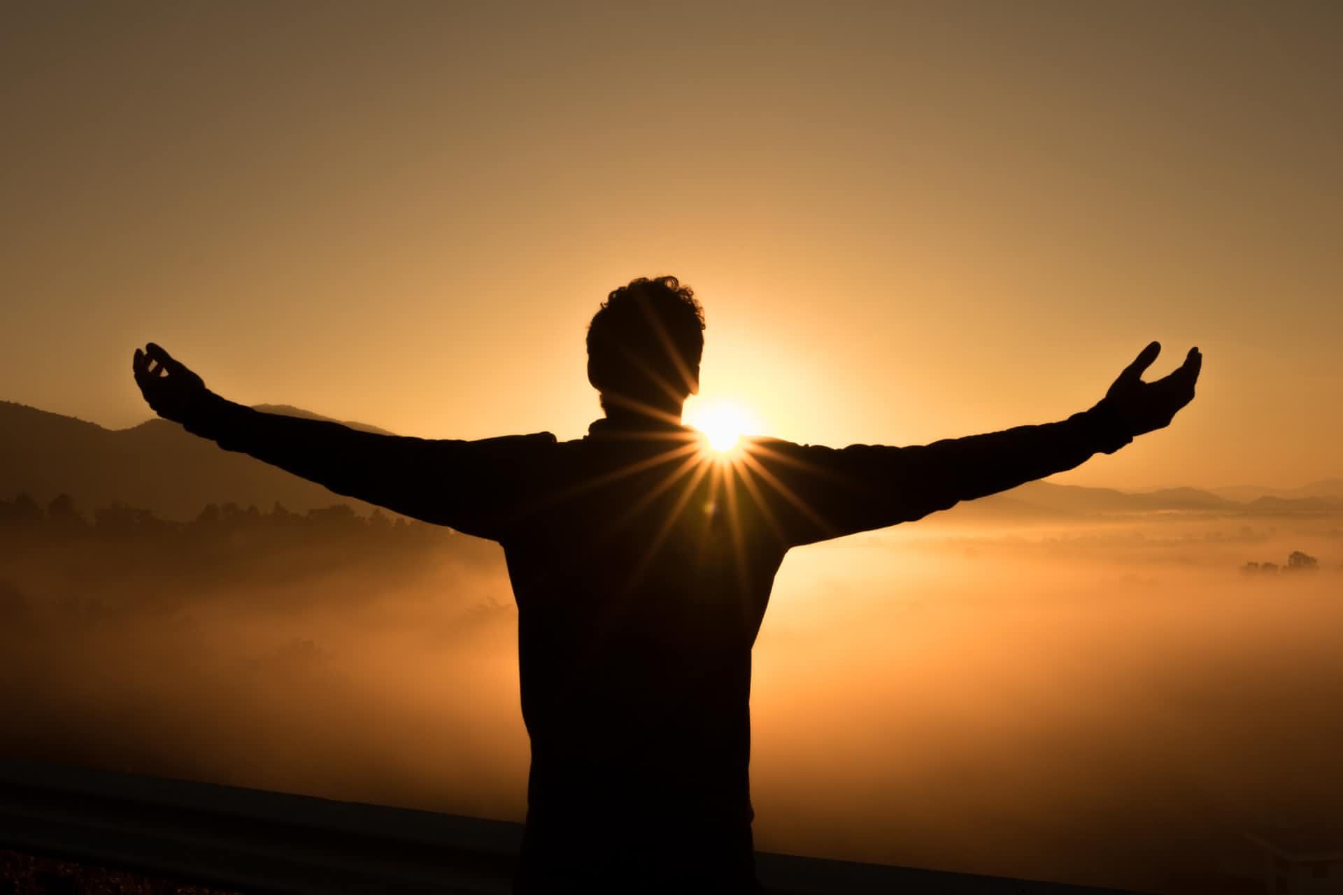 Ein Mensch öffnet beim Sonnenuntergang die Arme